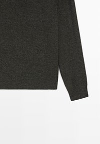 Maglione grigio scuro lavorato a maglia con scollo rotondo, maniche lunghe e finitura leggermente strutturata. Design senza cuciture all'orlo e ai polsini.