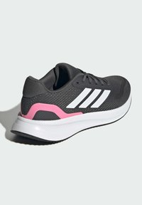 Czarne sportowe buty z białymi paskami, różowymi akcentami, teksturowaną siateczkową cholewką, miękką białą podeszwą środkową i wzorzystą czarną gumową podeszwą zewnętrzną.