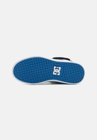 Plava podloga s gaznim slojem skate tenisice s DC logo u središtu, na bijeloj pozadini.