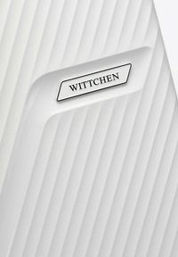 Maleta blanca de carcasa dura con textura estriada, que presenta un panel plateado grabado que dice "WITTCHEN". Acabado liso con un leve brillo.