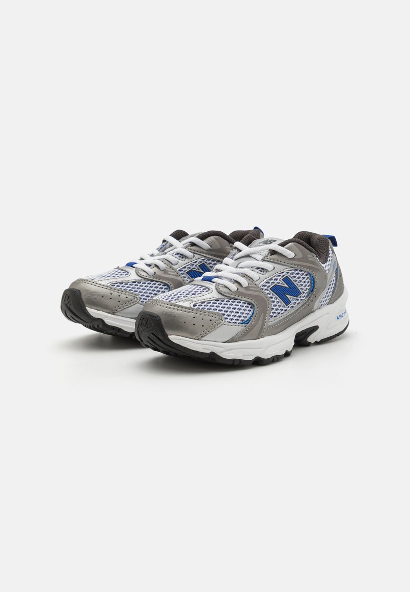 Zapatillas deportivas grises y azules con material de malla, que cuentan con cordones blancos, suelas de goma negras y un logo prominente en el lateral.
