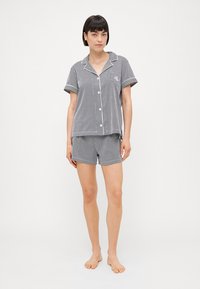 Randig pyjamas-set i grått och vitt, med korta ärmar, en knappar-up skjorta och matchande shorts i en avslappnad passform.