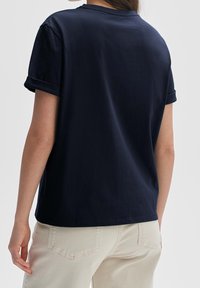 Maglietta in cotone blu navy con maniche corte arrotolate, scollatura a girocollo e vestibilità rilassata, mostrata di spalle.