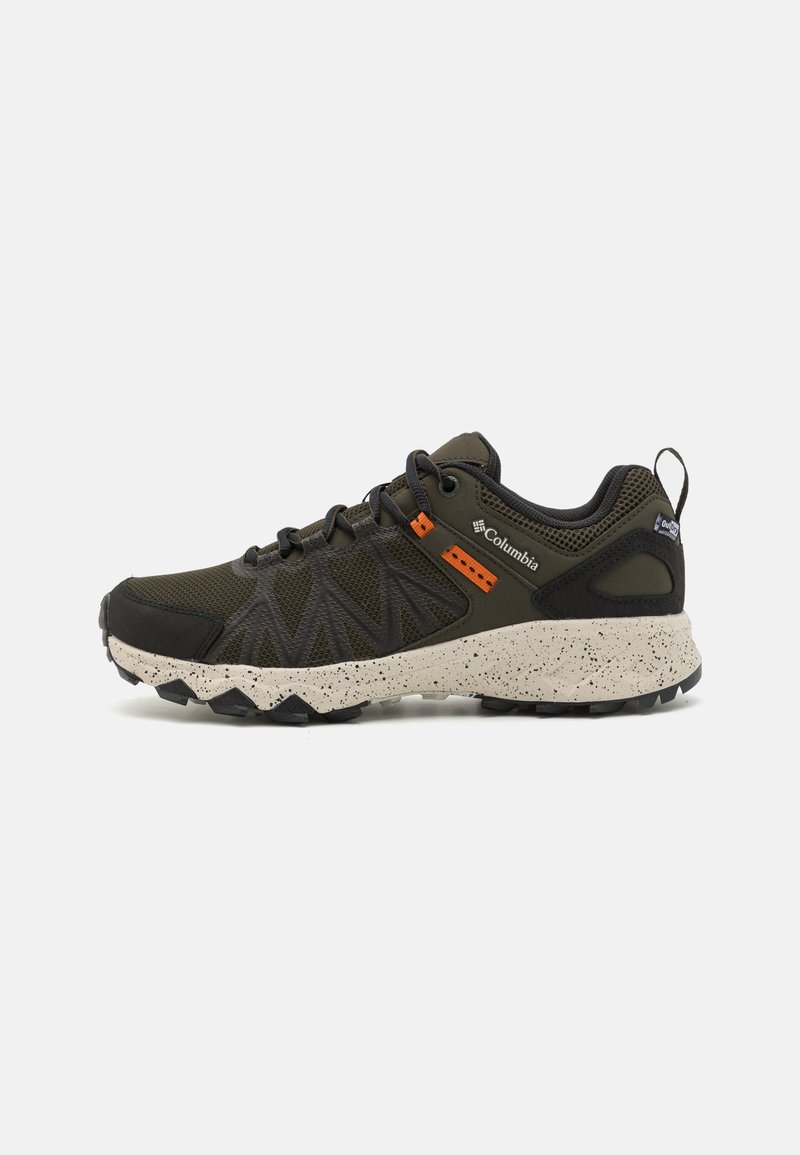 Baskets de sport vert foncé avec une tige en mesh texturé, des accents orange contrastants et une semelle beige mouchetée conçue pour l'adhérence et le soutien.
