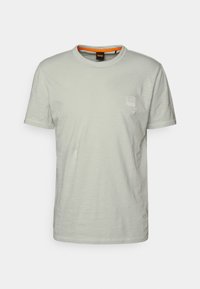 Ljusgrå T-shirt i mjukt tyg, med rund halsringning, korta ärmar och en liten logotypapplikation på vänster bröst.