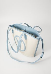 Krémová textilní taška s modro světle modrými koženými detaily, která má dvojité držáky a odnímatelný popruh na rameno, uvnitř zabezpečená kapsa na zip.