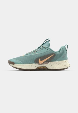 Nike Trail ATC batai, turintys šviesiai žalią viršutinę dalį, tekstūruotą tinklinę medžiagą, oranžinius akcentus, taškuotą pado vidurį ir tvirtą rudą pado dalį.