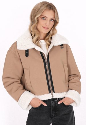 Kort beige jack met een fluffy witte kraag en manchetten, zwarte rits en zijzakken. Gemaakt van een zachte, gestructureerde stof.