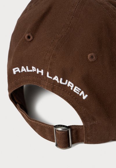 Brown fabric baseball cap with adjustable strap and silver metal buckle, embroidered with white "RALPH LAUREN" text on back.