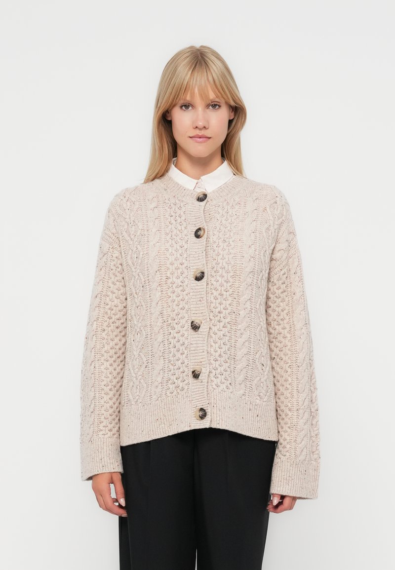 Strickjacke in hellem Beige mit strukturierten Zopfmuster und großen dunklen Knöpfen, mit einem lockeren Schnitt und gerippten Bündchen.