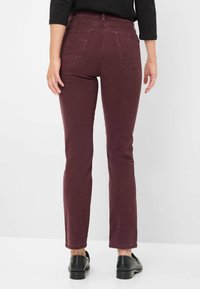 Bordeauxfarbene, gerade geschnittene Jeans mit mittelhoher Taille und zwei Gesäßtaschen, aus glattem Stoff. Der untere Saum ist leicht ausgefranst.