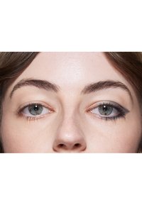 Två ögon närbild; vänster öga har metallisk grå ögonskugga, höger öga har en markant svart eyeliner med vingad form. Huden är ljus med en naturlig textur.