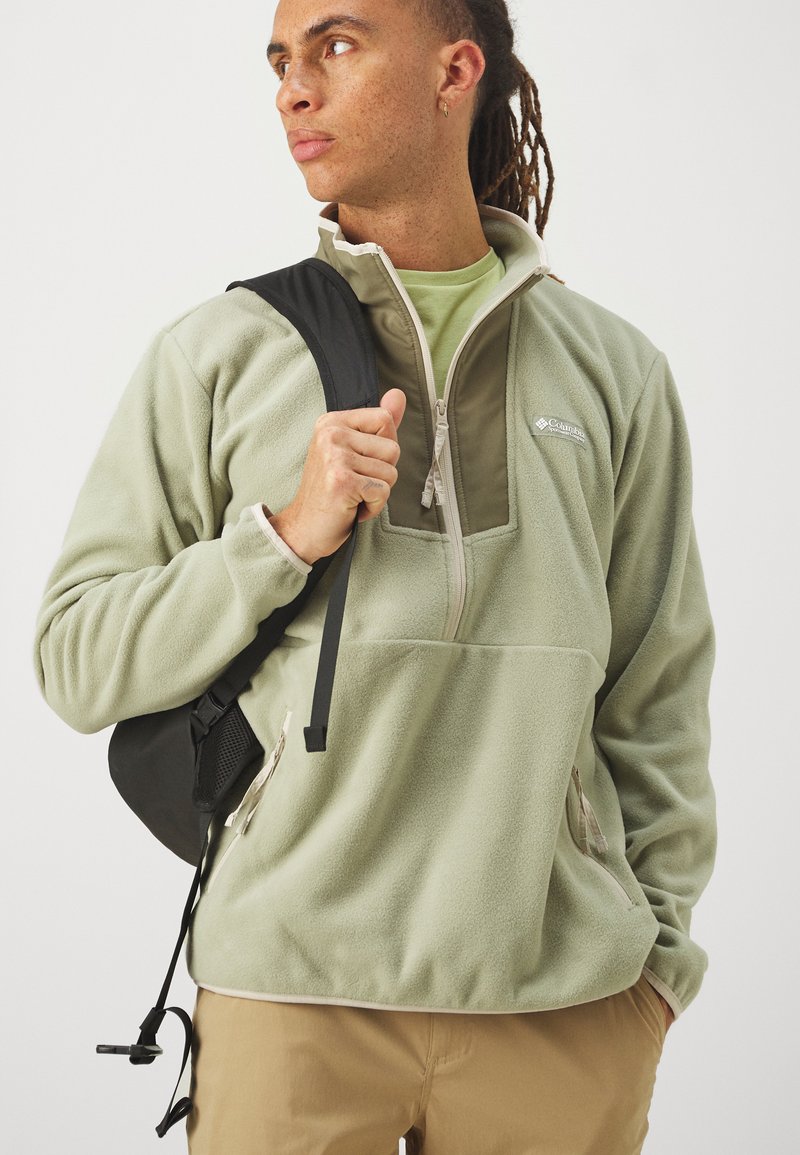 Fleece pullover in lichtgroen met een half-rits ontwerp, voorzien van zijzakken, tonale accenten en een klein logo op de borst.