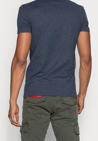 Mörkblå kortärmad t-shirt i mjukt tyg, tillsammans med olivgröna cargobyxor med flera fickor och detaljerad sömnad.