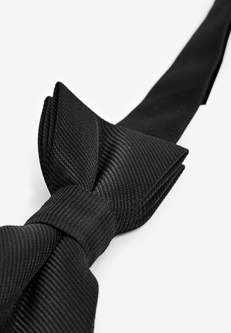 Sort butterflyknude lavet af struktureret stof, der har en klassisk form og et glat, lige bånd. Udsmykket med subtil ribbning.