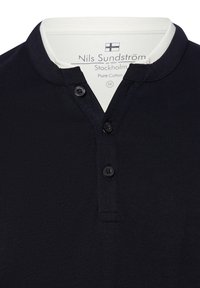 Dunkelblaues Poloshirt aus reiner Baumwolle, mit einem weißen Kragen und drei schwarzen Knöpfen, das eine einheitliche Textur und ein lässiges Design zeigt.