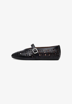 Black ballet flats with perforated detailing, featuring a rounded toe and a decorative strap with buckle accent. Made from synthetic material.