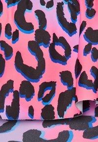 Leopardmönstrad tyg med en gradient i rosa som bas, med stora svarta fläckar som är accentuerade i blått, som visar en mjuk textur och levande färger.