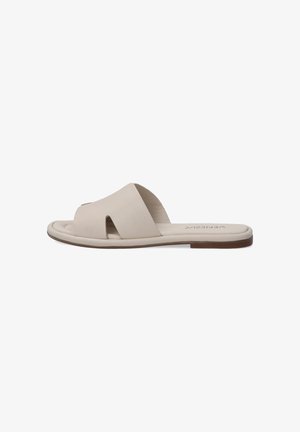 Beige slip-on sandal featuring a wide upper strap with cutout details, flat sole, and minimalistic design for comfort and ease of wear.