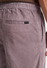 Corduroy shorts in light mauve with vertical ribbed texture, featuring a back pocket and elastic waistband for comfort.