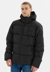Doudoune noire avec un col haut et une capuche ajustable. Comprend des sections matelassées, une fermeture éclair à l'avant et un minimum de marquage sur la poitrine gauche.