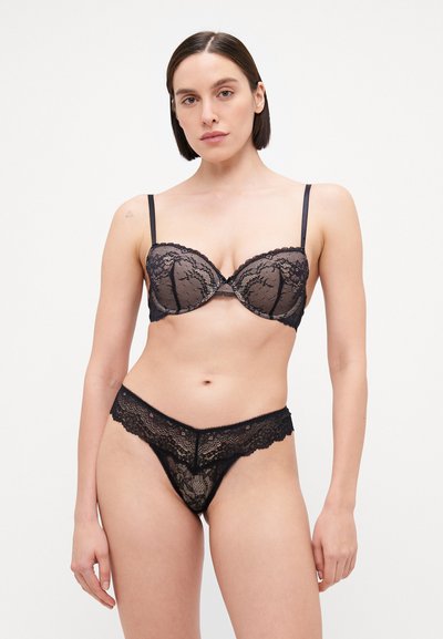 Black lace lingerie set featuring a balconette bra with underwire and matching thong. Intricate lace pattern and scalloped edges.