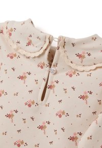 Beige babykleding met kleine roze en bruine bloemmotieven, gegolfde kraag en sluiting met één knoop op de achterkant van de hals.