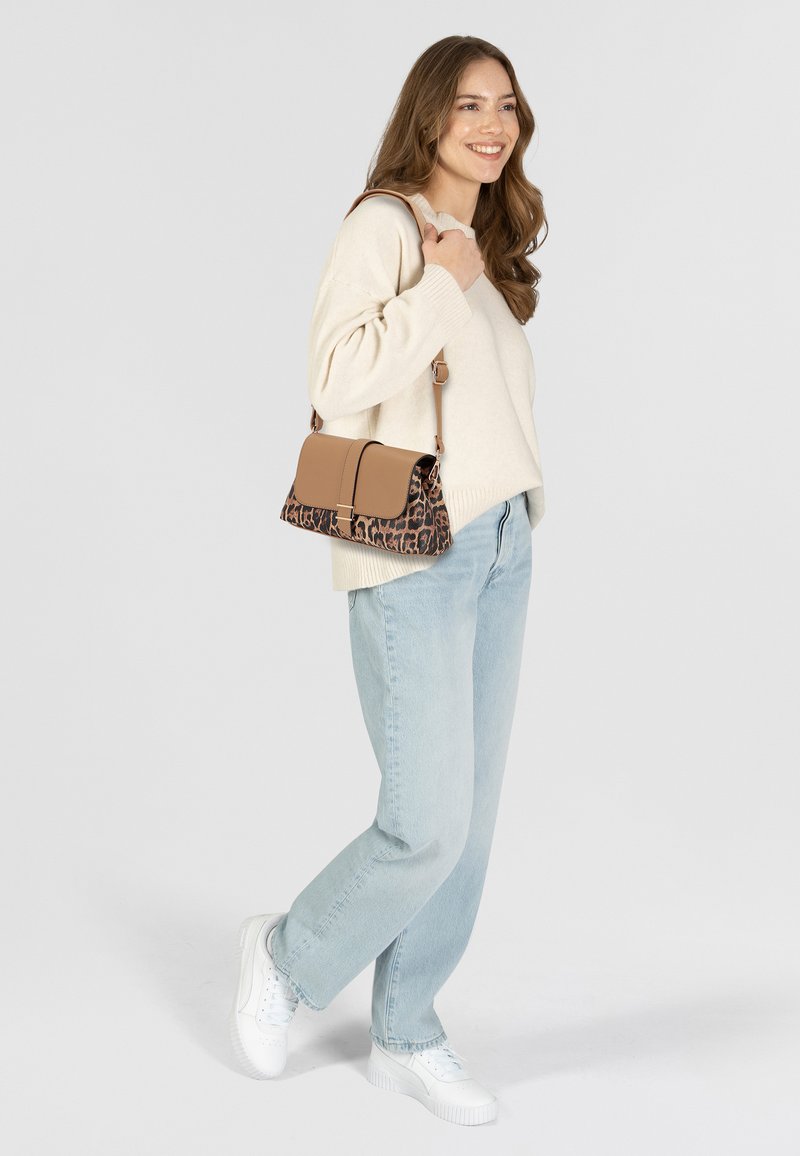 Borsa marrone e a stampa leopardata con tracolla staccabile, forma rettangolare, superfici lisce e testurizzate, indossata con jeans chiari e sneakers bianche.