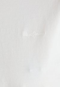Bílá bavlněná tričko s malým vyšívaným logem "Pepe Jeans" v bílé nitě na levé straně, s hladkou texturou.