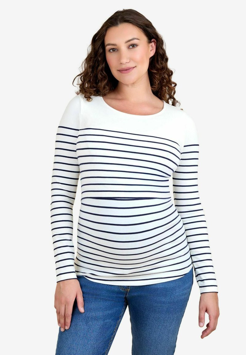 Langærmet graviditetstop lavet af hvidt stof med marineblå vandrette striber, med rund halsudskæring og tætsiddende design. Bæres med blå jeans.