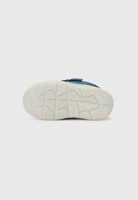 Schnürschuh mit Klettverschluss in Dunkelblau und weißer Gummisohle. Die Sohle hat ein strukturiertes Profil für besseren Halt. Schlichtes Design, ohne Verzierungen.
