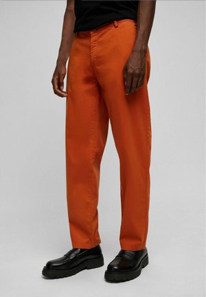 Oranje katoenen broeken met een rechte snit, voorzien van frontzakken en een platte voorkant, gecombineerd met zwarte chunky schoenen.