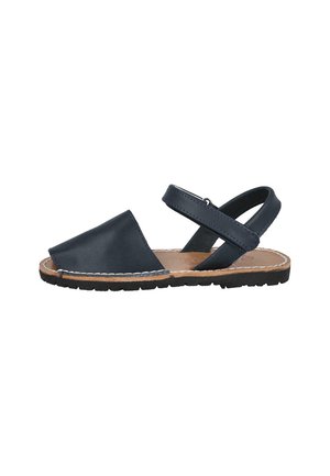 Sandal de cuero negro con punta cerrada, parte trasera abierta y una correa ajustable. La suela texturizada proporciona agarre y estabilidad.
