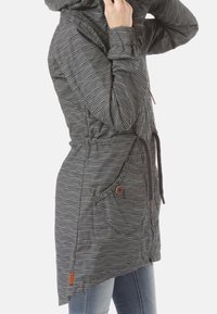 Giacca a cappuccio a righe con chiusura a zip, vita con cordoncino, due grandi tasche con dettagli a bottone, in bianco e nero. Tessuto morbido e texturizzato.