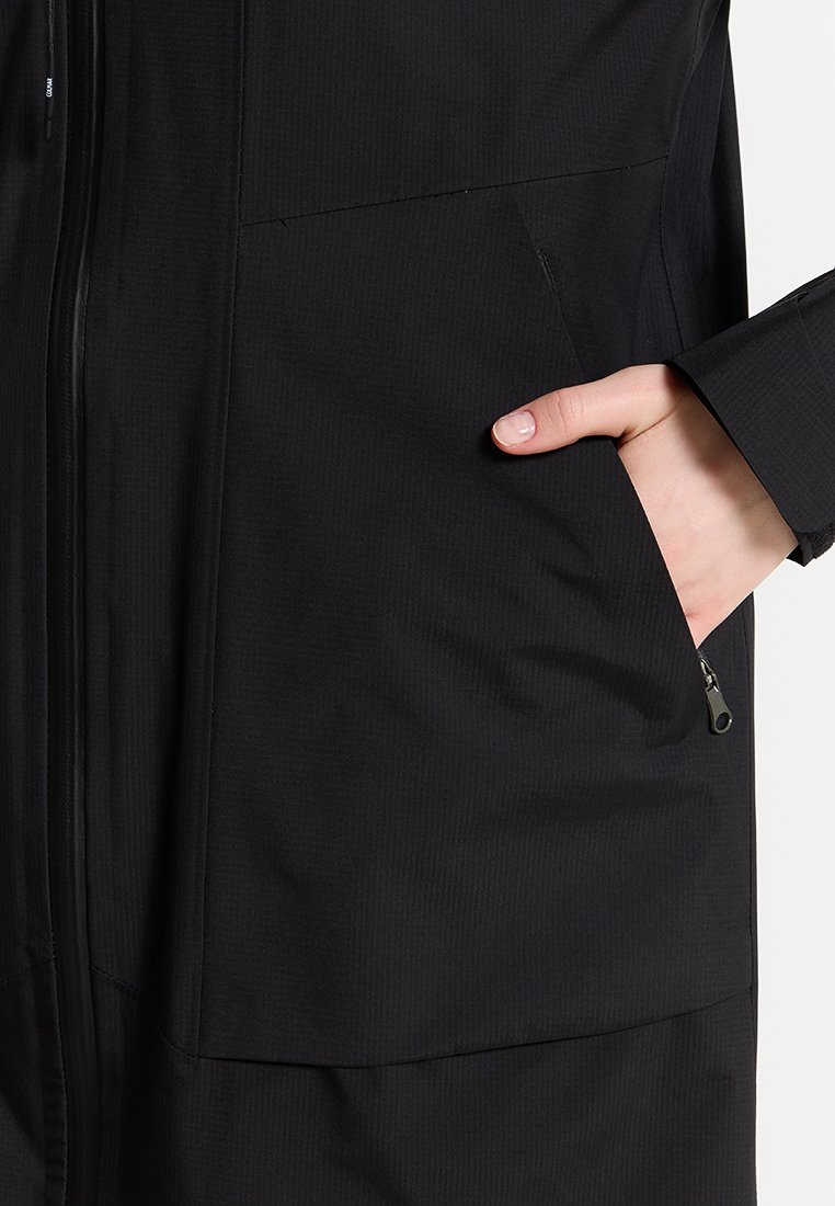 Giacca nera, leggera, con chiusura a zip, trama a coste e tasche anteriori. Le maniche presentano un leggero dettaglio a polsino.