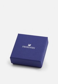 Swarovski-låda i texturerat blått papper med en silverlogga. Fyrkantig form med rena kanter, designad för smyckesförpackningar.