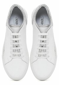 Valkoiset lenkkarit, joissa on sileä nahkapinta, hopeiset yksityiskohdat kauluksessa ja kimaltelevat nauhakohdat. Kuusi valkoista nauhaa.