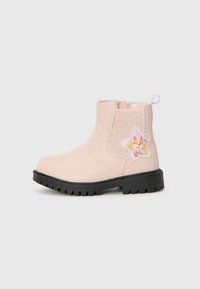 Bottine rose avec semelle noire, dotée d'un panneau latéral brillant et d'un badge représentant un personnage de dessin animé en forme d'étoile sur le côté extérieur.