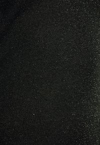 Μαύρο ύφασμα με λεπτή ασημένια γκλίτερ ομοιόμορφα κατανεμημένο στην υφαντή επιφάνεια, δημιουργώντας μια διακριτική λάμψη.