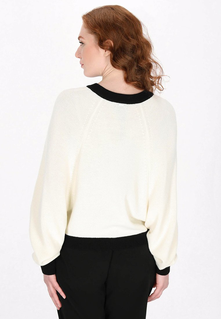Weißerstrickpullover mit einem schwarzen Rippkragen und -bündchen, der eine lockere Passform und eine glatte Textur bietet. Rückansicht gezeigt.