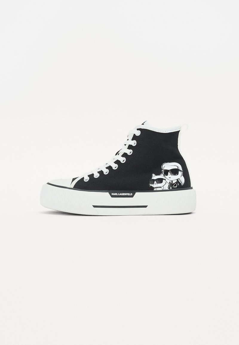 Høyhælte sneakers i svart lerret med hvit gummisåle og lisser. Har grafikk av to figurer med solbriller på siden.