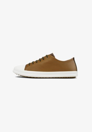 Bruine leren sneakers met een witte rubberen neuskap en tussenzool. Voorzien van olijfgroene veters en subtiele bruine accenten op de hiel. Platte zool.