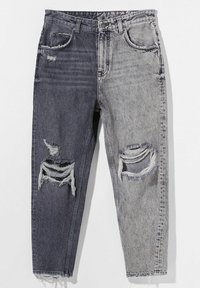 Denim jeans in a half black and half gray design, featuring distressed rips and frayed hems. Material is textured cotton with a worn appearance.