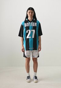 Túlméretes, rövid ujjú sportmez világoskék és fekete színben, rajta a "BOTTER" és a "27" felirattal. Fehér sorttal párosítva, amelyen aláírások találhatók.