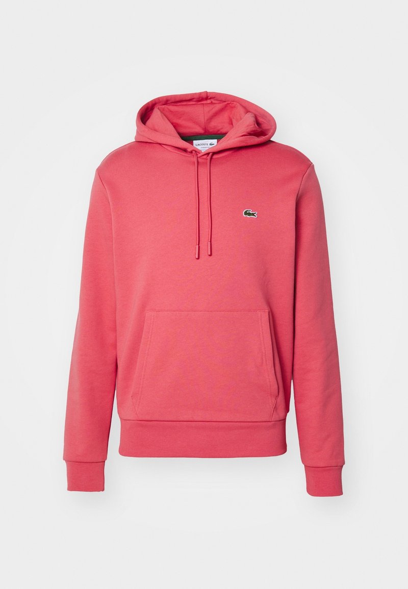 Sweat à capuche rose corail avec poche avant, cordons, poignets côtelés et logo crocodile Lacoste sur la poitrine gauche.