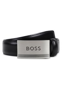 Μαύρη δερμάτινη ζώνη με ασημένια ορθογώνια αγκράφα που φέρει το όνομα "BOSS" και οριζόντιες γραμμές διακοσμητικά. Ομαλή υφή, κλασικός σχεδιασμός.