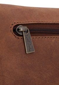 Pochette in pelle marrone con superficie texturizzata, chiusura con zip e un'etichetta metallica con inciso "Austi Leder". I bordi cuciti sono visibili.