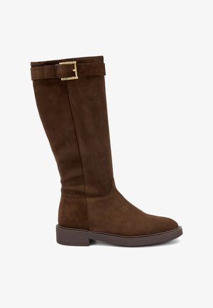 Stivale in suede marrone al ginocchio con punta arrotondata, suola piatta e dettaglio con fibbia vicino al polsino. Texture liscia con cuciture minime.