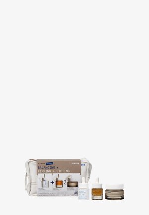 Set di prodotti per la cura della pelle Korres che include sieri riequilibranti e rassodanti e una crema idratante, presentati con una pochette in tessuto bianco e una scatola per il packaging.