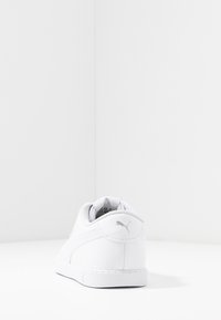 Bílé tenisky s hladkým koženým svrškem, zaoblenou špičkou a diskrétním logem na patě. Jednoduchý design s tonálním prošíváním a síťovinovými detaily.